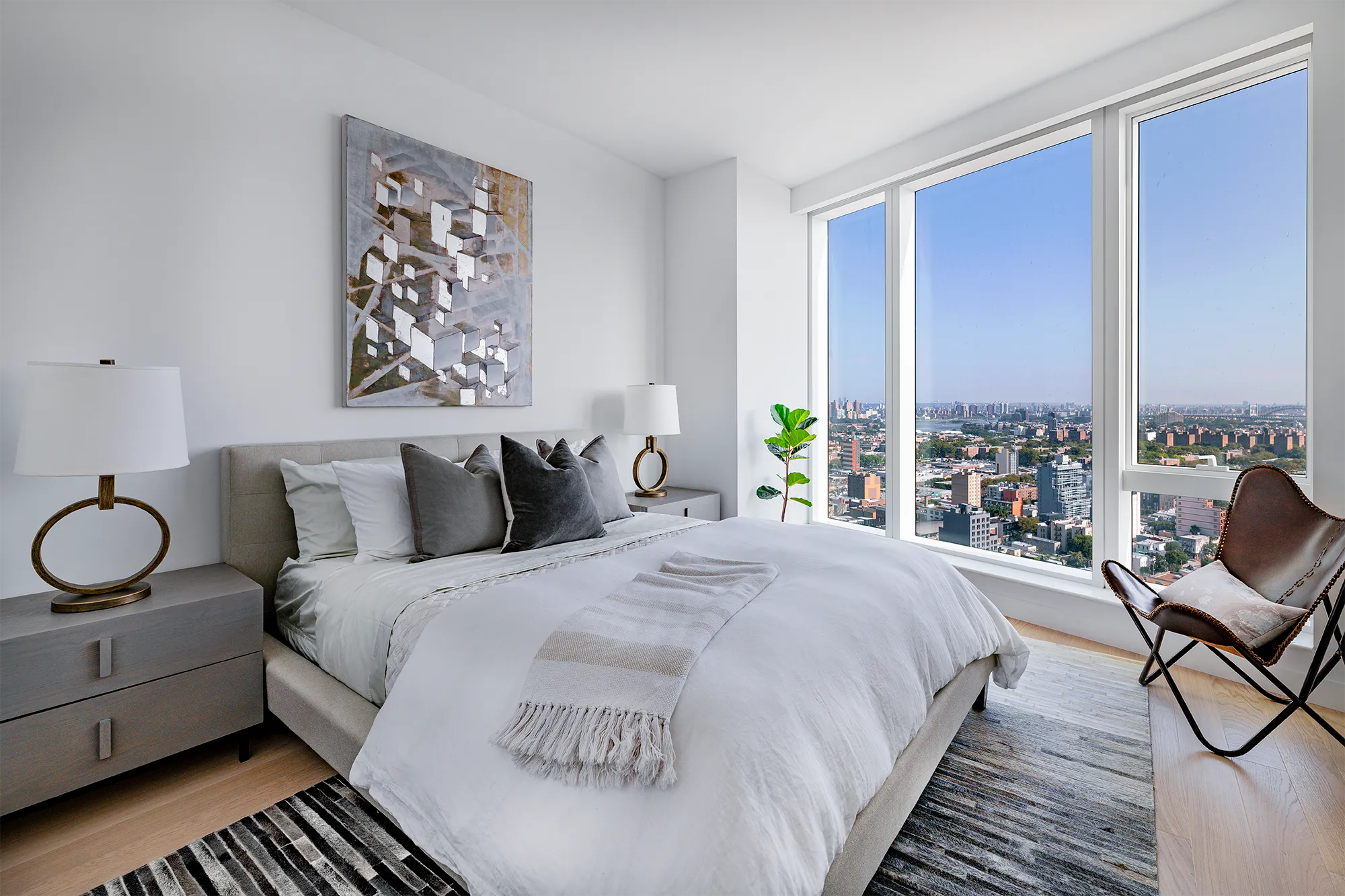 Open modern bedroom with king-size bed and floor-to-ceiling windows and desk with chair